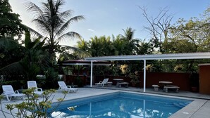Une piscine avec des chaises longues et un espace patio couvert.