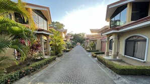 Une rue résidentielle bordée de maisons modernes, avec un trottoir pavé et une végétation luxuriante.