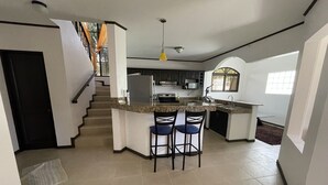Une cuisine moderne dotée d’un îlot central, de tabourets de bar et d’un escalier menant à un autre niveau.