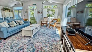A living room with a blue sofa, a coffee table, a TV stand, and a ceiling fan. - Bethany Beach * 4BR Luxury House (Bethany Beach)