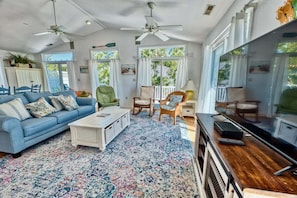 A living room with a blue sofa, a coffee table, a TV stand, and a ceiling fan.