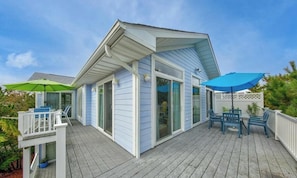 A house with a covered deck, sliding glass doors, and outdoor furniture.