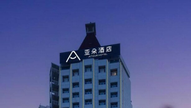 A multi-story hotel with a prominent A-shaped logo at the top. - Atour Hotel (Ürümqi)