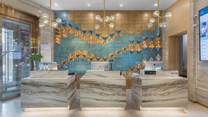 A hotel reception area with marble counters, a geometric patterned wall, and pendant lighting. - Atour Hotel (Ürümqi)