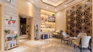 A hotel lobby with a reception desk, seating area, and a geometric wall design. - Atour Hotel (Ürümqi)