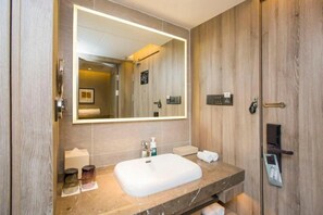 Un baño moderno con un espejo grande, un lavabo blanco y un mueble de tocador de madera.