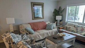 Un salon comprenant un canapé, deux fauteuils, une table basse et un tableau encadré accroché au mur.