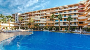 A hotel with a large swimming pool surrounded by lounge chairs and palm trees. - Balcon de Los Gigantes 2A016 poolview (Acantilados de Los Gigantes)