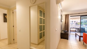 A hotel room with a sliding door leading to a balcony, a clock on the wall, and a dining area with a table and chairs. - Balcon de Los Gigantes 2A016 poolview (Acantilados de Los Gigantes)