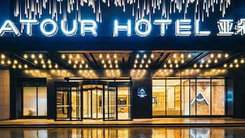 A hotel entrance with a modern design, featuring a neon sign and a glass facade.