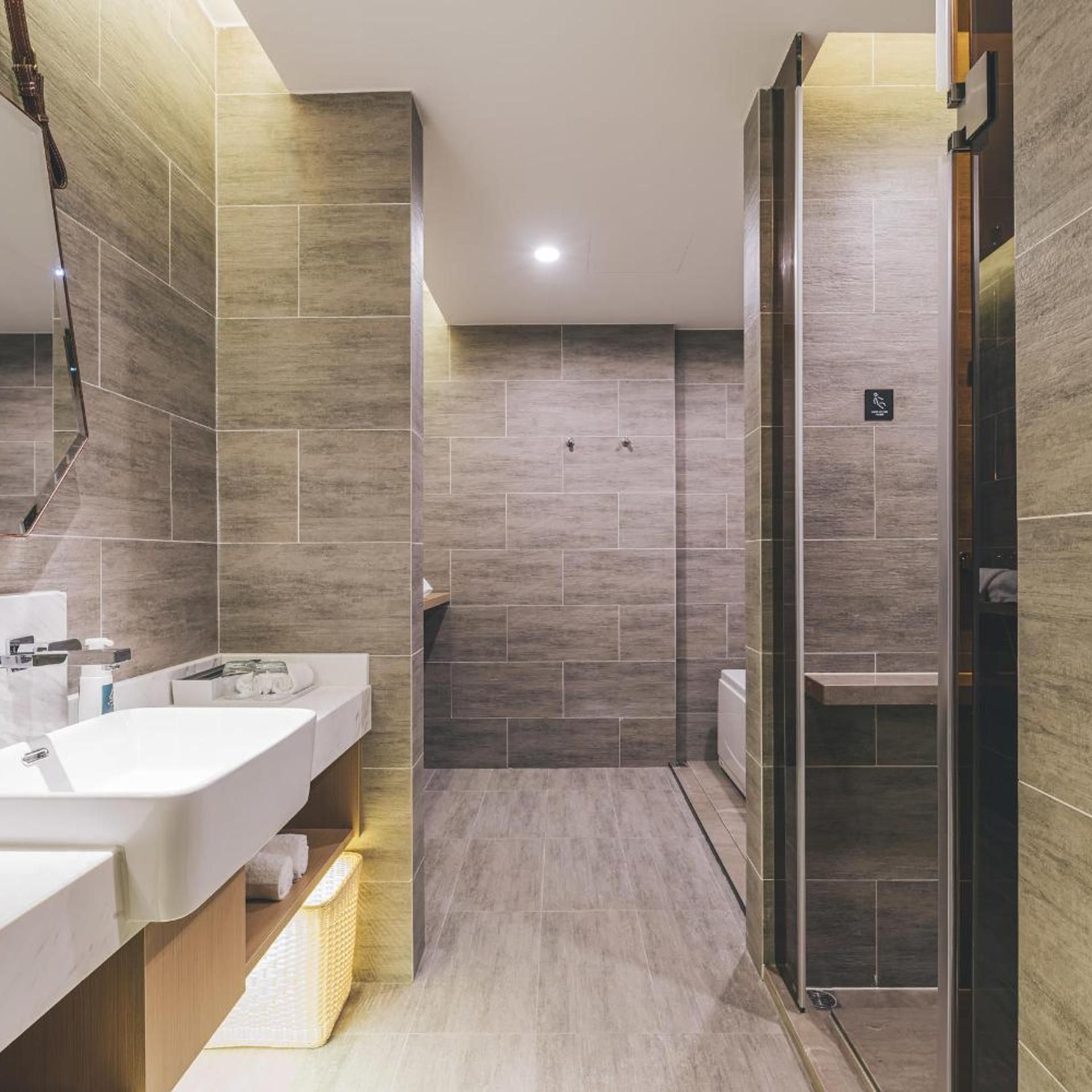A modern bathroom with a large mirror, a sink, and a shower area.