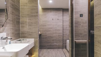 A modern bathroom with a large mirror, a sink, and a shower area.