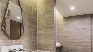 Un baño moderno con un espejo grande, dos lavamanos y una zona de ducha.