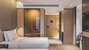 A modern hotel room with a large bed, a desk, and a wardrobe.