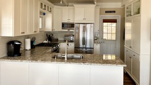 Una cocina moderna con armarios blancos, electrodomésticos de acero inoxidable y encimera de granito.