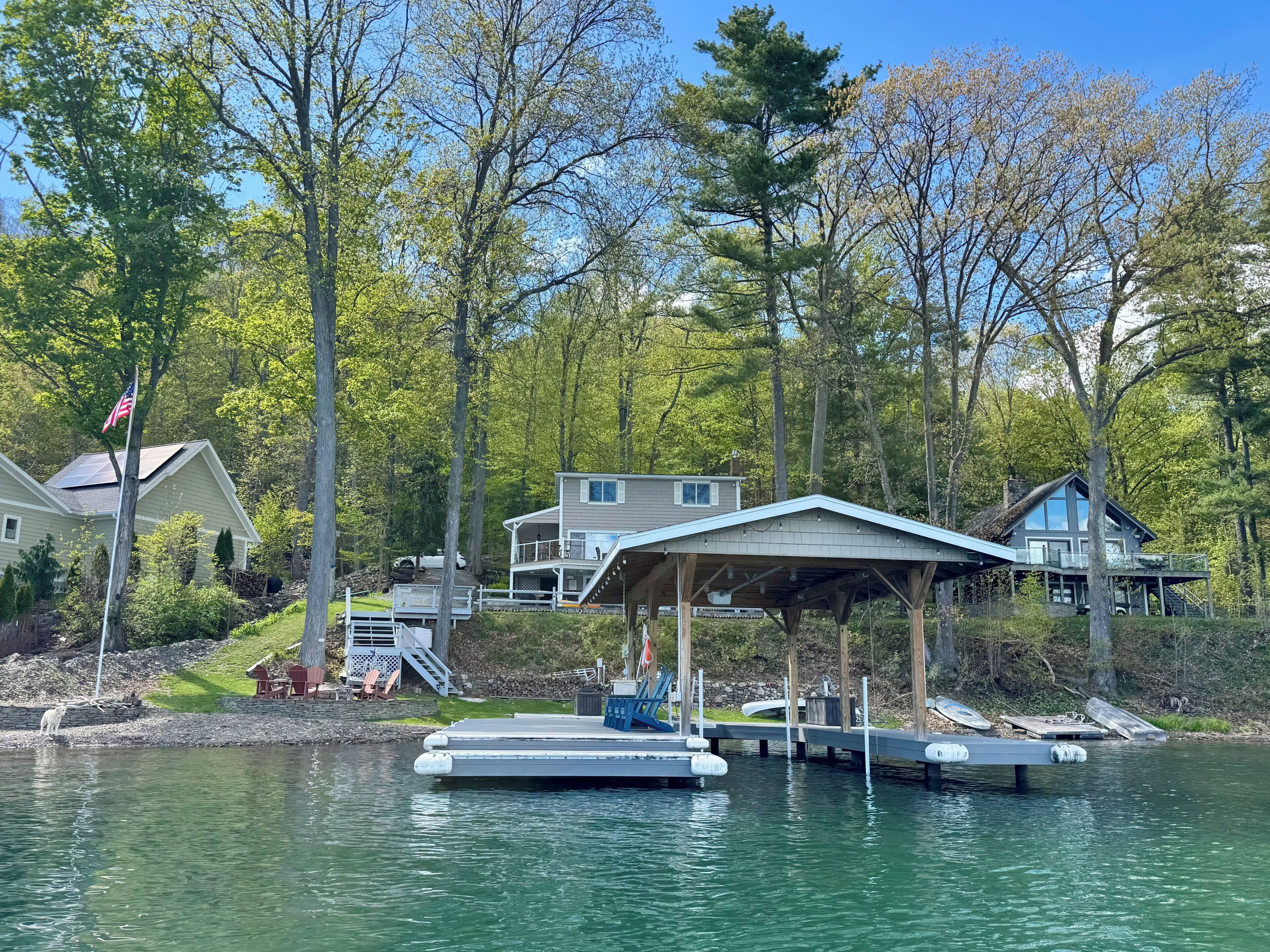 Une propriété au bord du lac, dotée d’un quai, d’un espace extérieur aménagé et couvert, et d’une maison avec une grande terrasse.