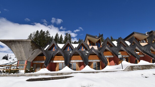 A modern hotel with a unique architectural design featuring multiple peaks and a ski lift in the background.