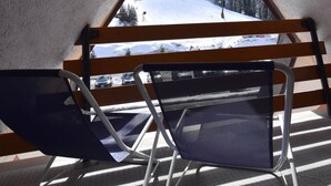 An interior view of a ski lodge with a triangular window overlooking a snowy mountain.