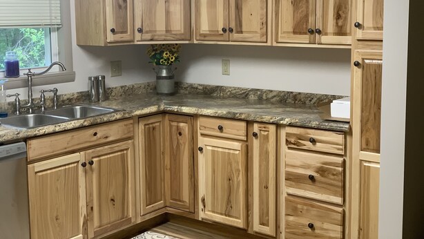 A kitchen with wooden cabinets, a granite countertop, a sink, and a window with blinds. - Cottage in the Woods (Warfordsburg)