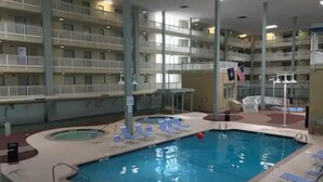 An indoor swimming pool with multiple levels of balconies, lounge chairs, and a flag. - 2BD/2BATH Villa! Near Beach! HHR Building 1! (Hilton Head Island)