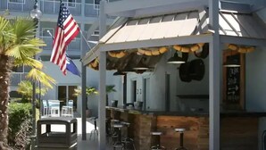 An outdoor seating area with a bar, American flags, and a view of a building in the background. - 2BD/2BATH Villa! Near Beach! HHR Building 1! (Hilton Head Island)