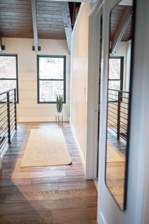 Stylish hallway with a white rug, large windows, and a potted plant.