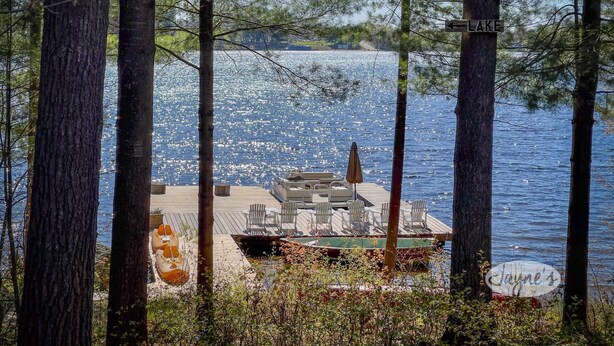 A dock with chairs and tables, surrounded by trees, with a sign indicating 'LAKE'.