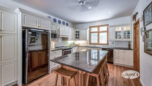 A spacious kitchen with white cabinetry, a central island, and a ceiling fan.