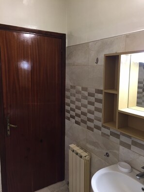 Een bad/douchecombinatie, handdoeken, toiletpapier