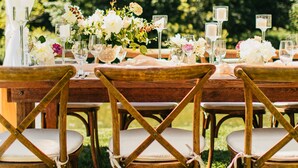 Ein Holzespeisesaal mit Stühlen, umgeben von floralen Dekorationen und Kerzen.