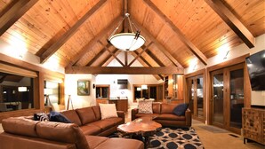 A spacious living area with a high wooden ceiling, leather sofas, a coffee table, and a patterned rug. - River's Edge Retreat by North Bend Escapes (Fall City)