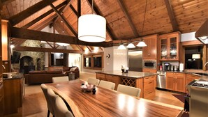 A spacious kitchen with wooden beams, a large island, and modern appliances. - River's Edge Retreat by North Bend Escapes (Fall City)