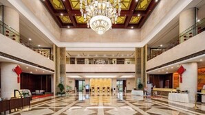A spacious lobby with a high ceiling, a large chandelier, and a check-in counter. - Dongtai Guest House (Dongtai)