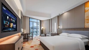 A hotel room with a bed, a TV mounted on the wall, a desk, and a chair. - Dongtai Guest House (Dongtai)