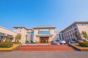 Un hotel moderno con una entrada destacada, varios pisos y cielo despejado.
