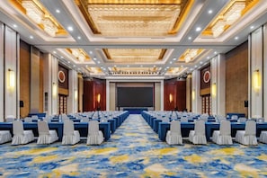 A conference room with rows of tables and chairs, a large screen, and a carpeted floor. - Dongtai Guest House (Dongtai)