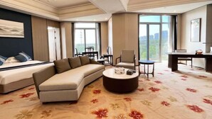 A hotel room with a bed, sofa, round coffee table, dining table, chairs, and large windows offering a city view. - Dongtai Guest House (Dongtai)