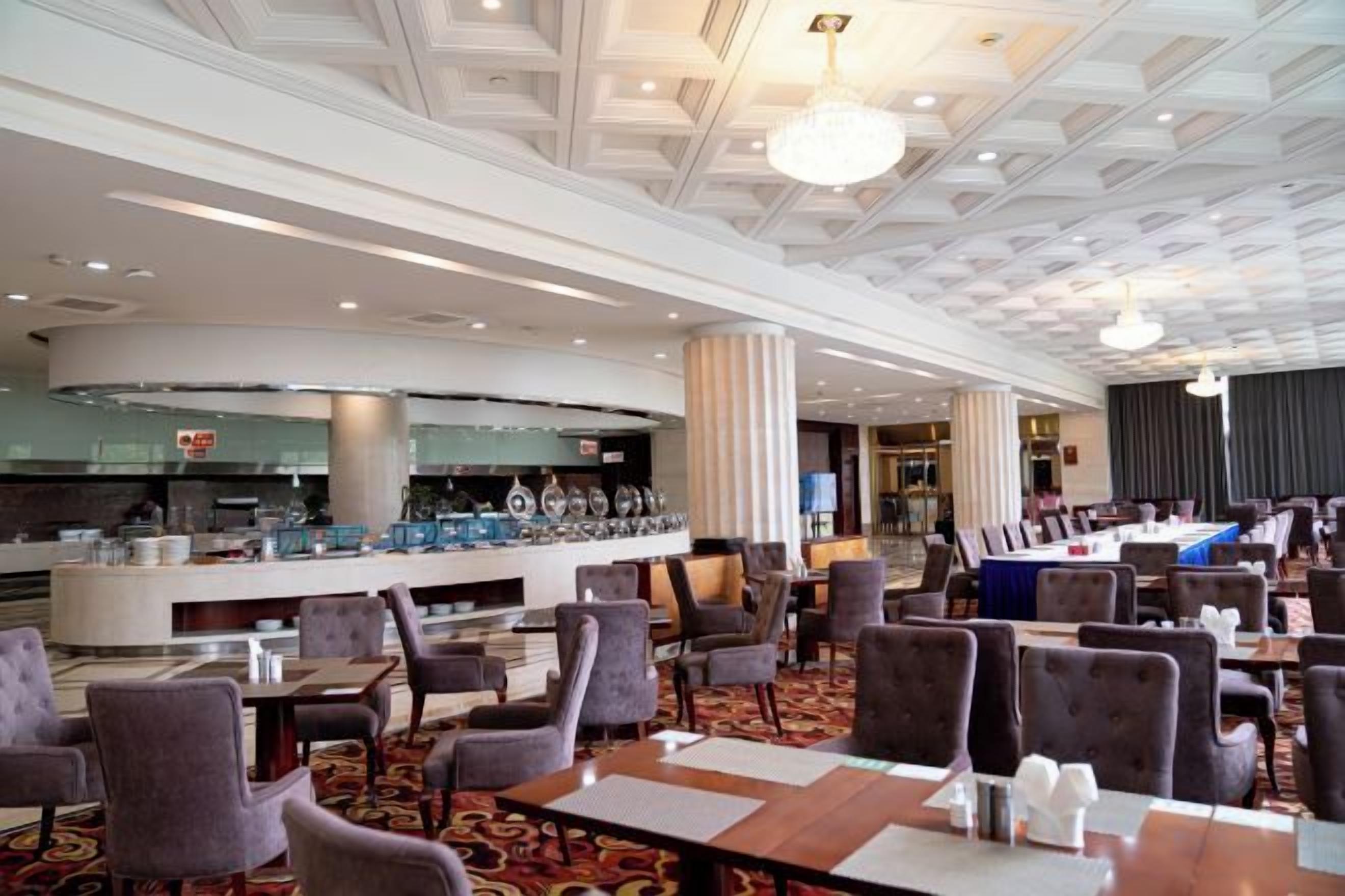 Eine Hotelhalle mit Barbereich, Sitzgelegenheiten und einem modernen Deckenstil.