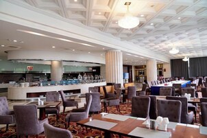 A hotel lobby with a bar area, seating arrangements, and a modern ceiling design.