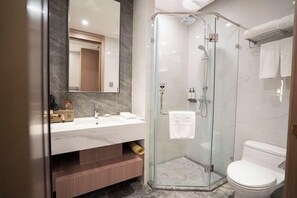 Un baño moderno con cabina de ducha de vidrio, inodoro blanco y tocador de mármol.