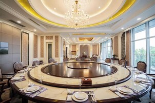 Un salón de conferencias con una mesa redonda, sillas y una araña.