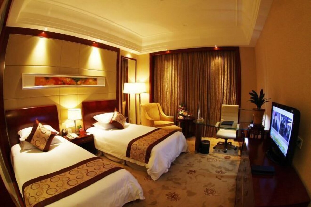A hotel room with two beds, a desk with a computer, a TV, and a chair.