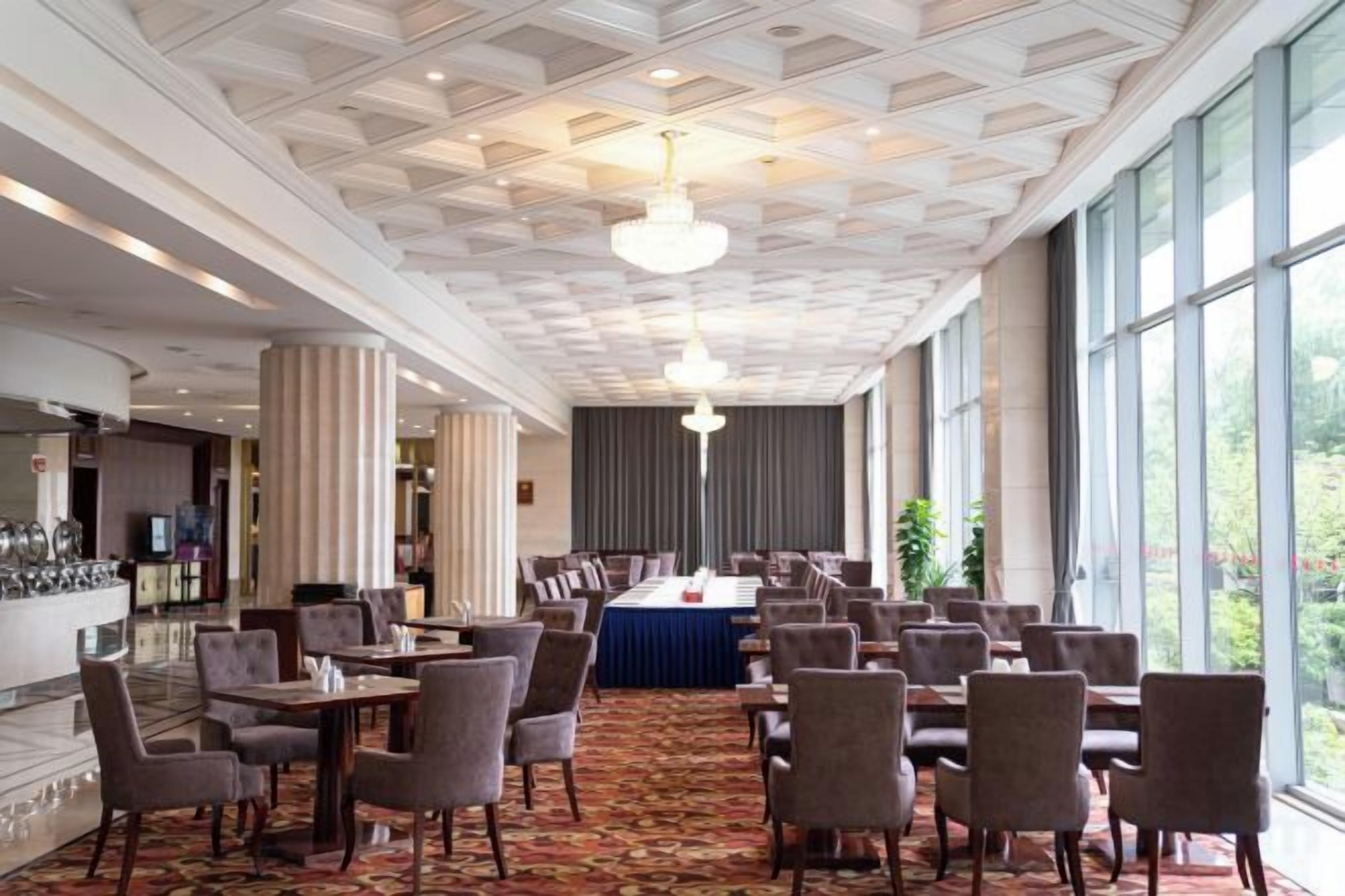 A hotel dining area with a long table, multiple chairs, and a bar counter.