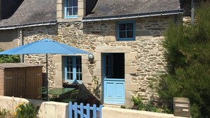 A stone building with a blue door and windows, a wooden shed, and a blue umbrella. - Fisherman's house 50 m from the sea (Piriac-sur-Mer)