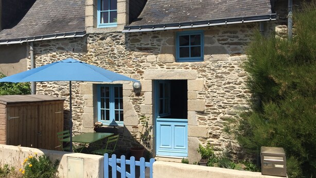 A stone building with a blue door and windows, a wooden shed, and a blue umbrella. - Fisherman's house 50 m from the sea (Piriac-sur-Mer)