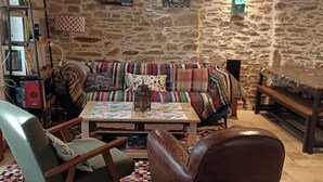 A cozy living room with a stone wall, a colorful sofa, a wooden coffee table, and a leather armchair. - Fisherman's house 50 m from the sea (Piriac-sur-Mer)