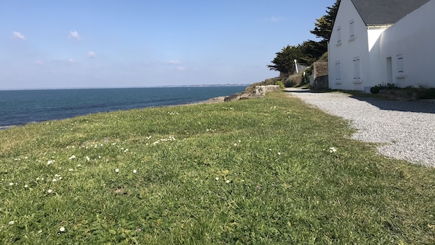 A coastal property with a gravel path leading to a white building with multiple windows, overlooking the sea. - Fisherman's house 50 m from the sea (Piriac-sur-Mer)