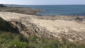 A rocky beach with a clear view of the sea and distant buildings. - Fisherman's house 50 m from the sea (Piriac-sur-Mer)