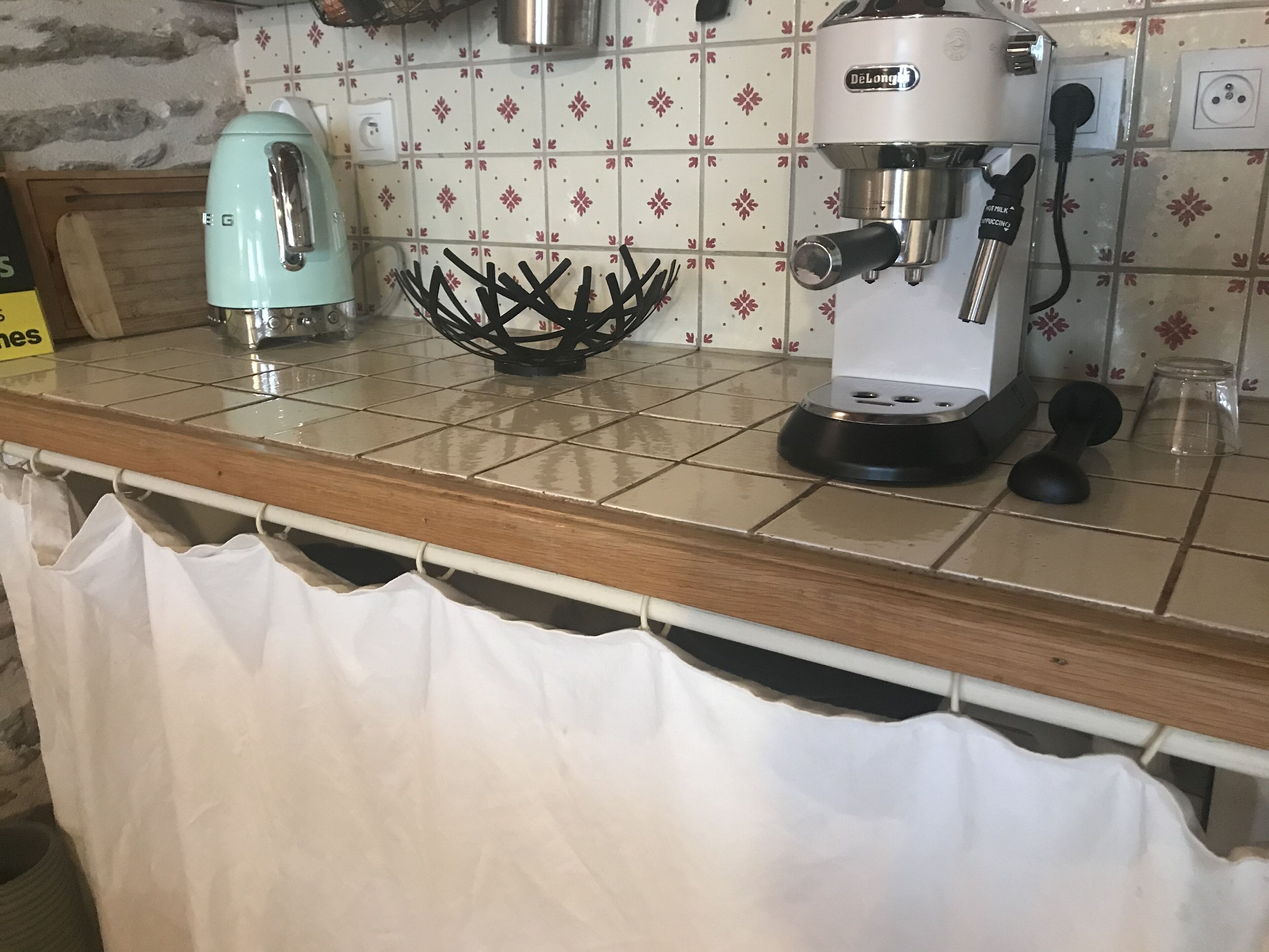 A kitchen counter with a coffee maker, a kettle, and a decorative metal bowl.