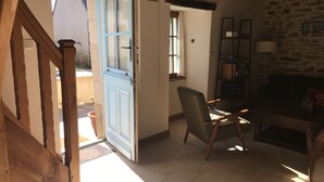 A room with a wooden staircase, a blue door, a chair, a table, and a stone wall. - Fisherman's house 50 m from the sea (Piriac-sur-Mer)